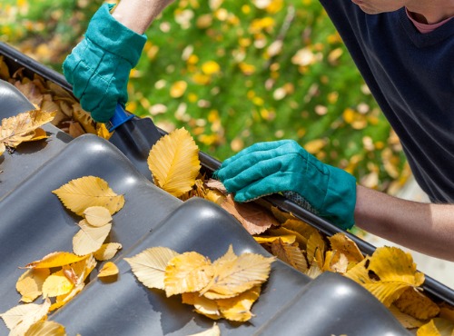 A roofer cleans gutters, which is one of the services Popejoy offers, as well as residential roofing in Normal IL
