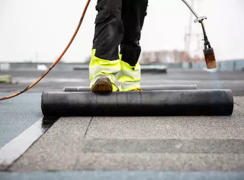 A worker is seen repairing a flat roof. Popejoy Roofing performs Flat Roof Repair in Bloomington IL.